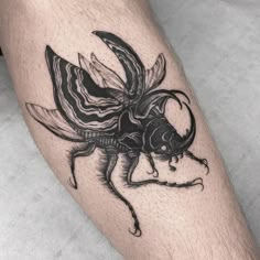 a man's leg with a black and white insect tattoo on the side of his leg