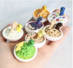 a person's hand holding several miniature food items in small bowls on top of each other