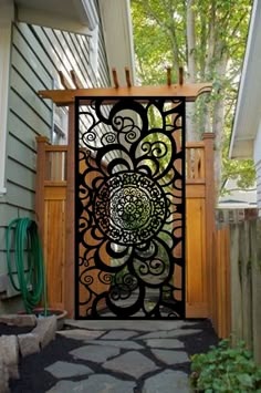 an intricate iron gate on the side of a house in front of a green hose