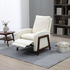 a white recliner chair sitting on top of a rug in front of a book shelf