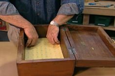 a man is working on an old wooden box with paper in the bottom and inside