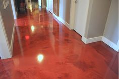 an empty hallway with shiny red floors and white trim on the walls is seen in this image