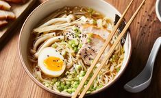 a bowl of ramen with chopsticks and an egg on the side next to some bread