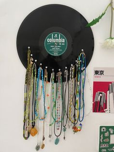 a record with many necklaces hanging from it's side next to a flower