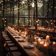 a long table with candles and plates on it in the middle of a wooded area