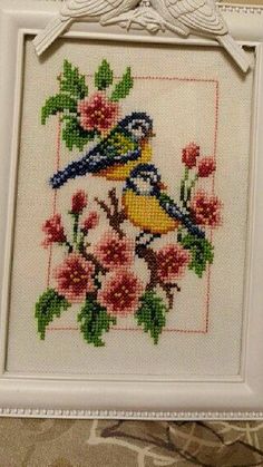 a cross stitch picture frame with a bird and flowers on it