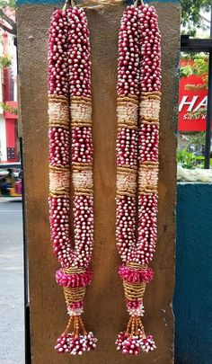 two necklaces made out of beads hanging from the side of a building