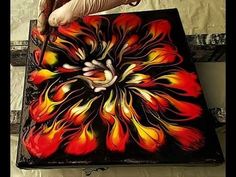 a person is painting on a piece of art that looks like flames and hands are reaching for it