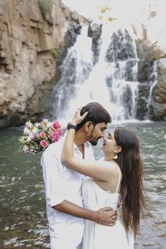 a man and woman standing in front of a waterfall