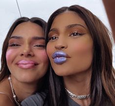 two women with makeup on their faces posing for the camera