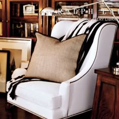 a white chair sitting in front of a book shelf filled with books