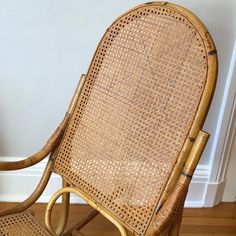 a wicker rocking chair sitting on top of a hard wood floor next to a white wall