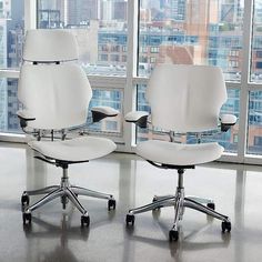 two white office chairs facing each other in front of large windows with city view behind them