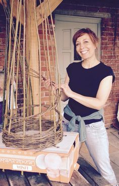 a woman standing next to a basket made out of bamboo sticks