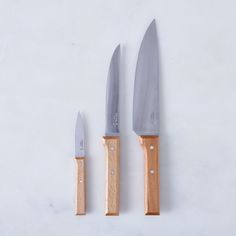 two knives are next to each other on a white surface with wood handles and blades