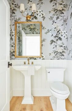 a white toilet sitting next to a sink in a bathroom under a mirror above it