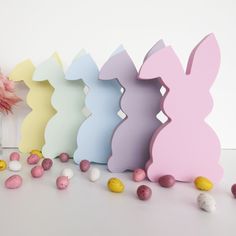 an assortment of colorful easter eggs in front of a white wall with pink and yellow candies