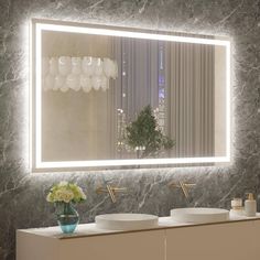 a bathroom vanity with two sinks and a large mirror above it that has lights on