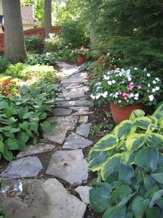 a stone path surrounded by flowers and trees