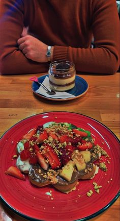 a man sitting at a table in front of a red plate with food on it