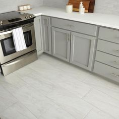 a kitchen with gray cabinets and white counter tops, stainless steel stove and dishwasher