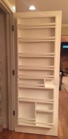 an empty white bookcase in the corner of a room with wooden floors and walls