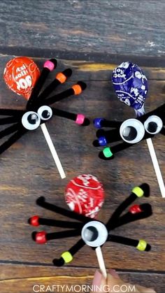 three spider lollipops are on a wooden table and one is made out of candy