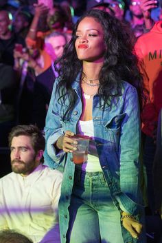 a woman standing in front of a crowd holding a drink