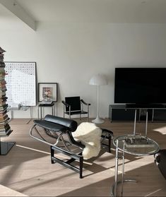 a living room filled with lots of furniture and books on top of a hard wood floor