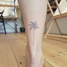 a small palm tree tattoo on the ankle is shown in this photo, it looks like someone's feet