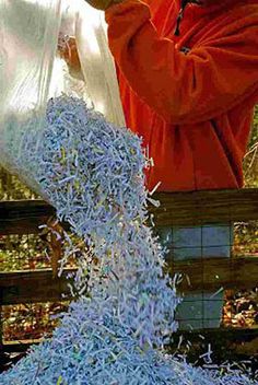 a man in an orange shirt is making something out of shredded paper and plastic bags