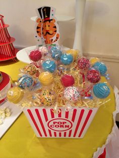 a popcorn box filled with assorted candys on top of a yellow table cloth