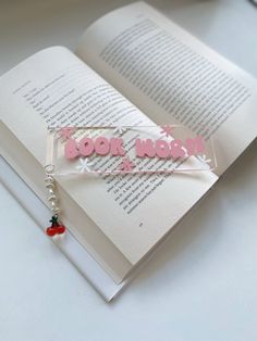 an open book with the words book and now on it next to a beaded charm