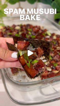 a person holding up a piece of food in a glass dish with the words spam musubi bake above it