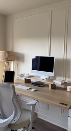 a desk with a computer monitor, keyboard and mouse on it next to a lamp