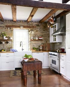 a rustic kitchen with white cabinets and wood flooring is pictured in this image, there are pots on the stove