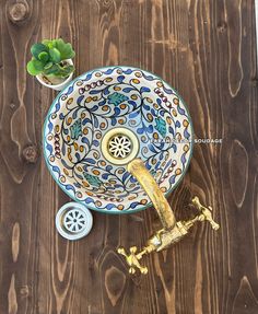 a decorative sink on top of a wooden table next to a small potted plant