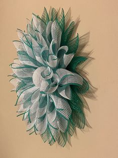 a green and white flower hanging on the wall next to a brown wall with a tan background