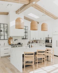 an open kitchen with white cabinets and wooden beams on the ceiling, along with stools