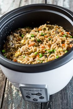 a close up of a rice dish in a crock pot on a wooden table