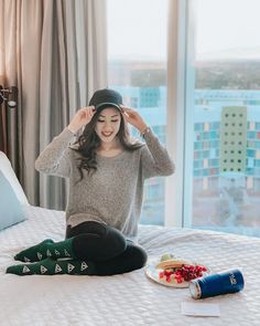 a woman sitting on top of a bed next to a plate of food