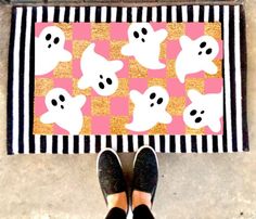 a person standing in front of a door mat with ghost faces on it