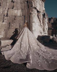 a woman in a wedding dress standing by some rocks