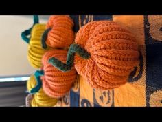 there are three pumpkins on the wall hanging from it's hooks, and one is knitted to look like yarn