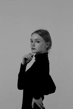 a black and white photo of a woman with her hand on her chin