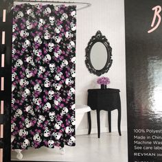 a black and white bathroom with skulls on the shower curtain next to a vanity table