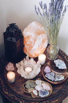 a table topped with crystals and candles next to a vase filled with lavenders on top of a wooden table