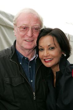 an older man and young woman posing for a photo in front of a white tent