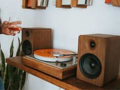 a person is holding a glass near a record player and other items on a shelf