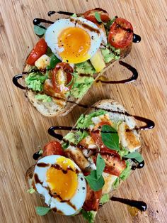 two toasted sandwiches with eggs, tomatoes and lettuce on wooden cutting board